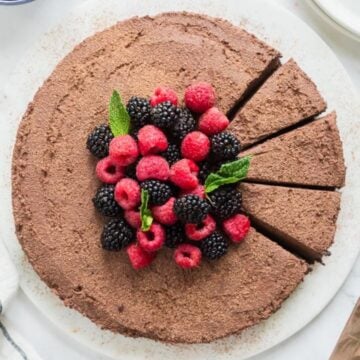 A chocolate mousse cake topped with berries and cut into slices.