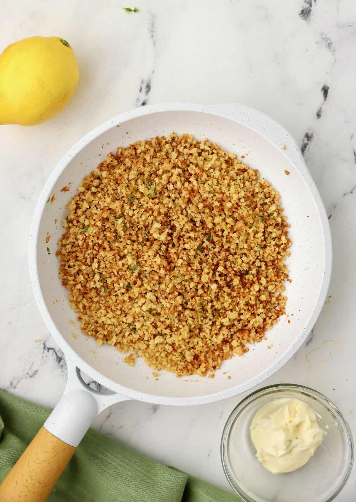 A white skillet full of toasted panko and butter. 