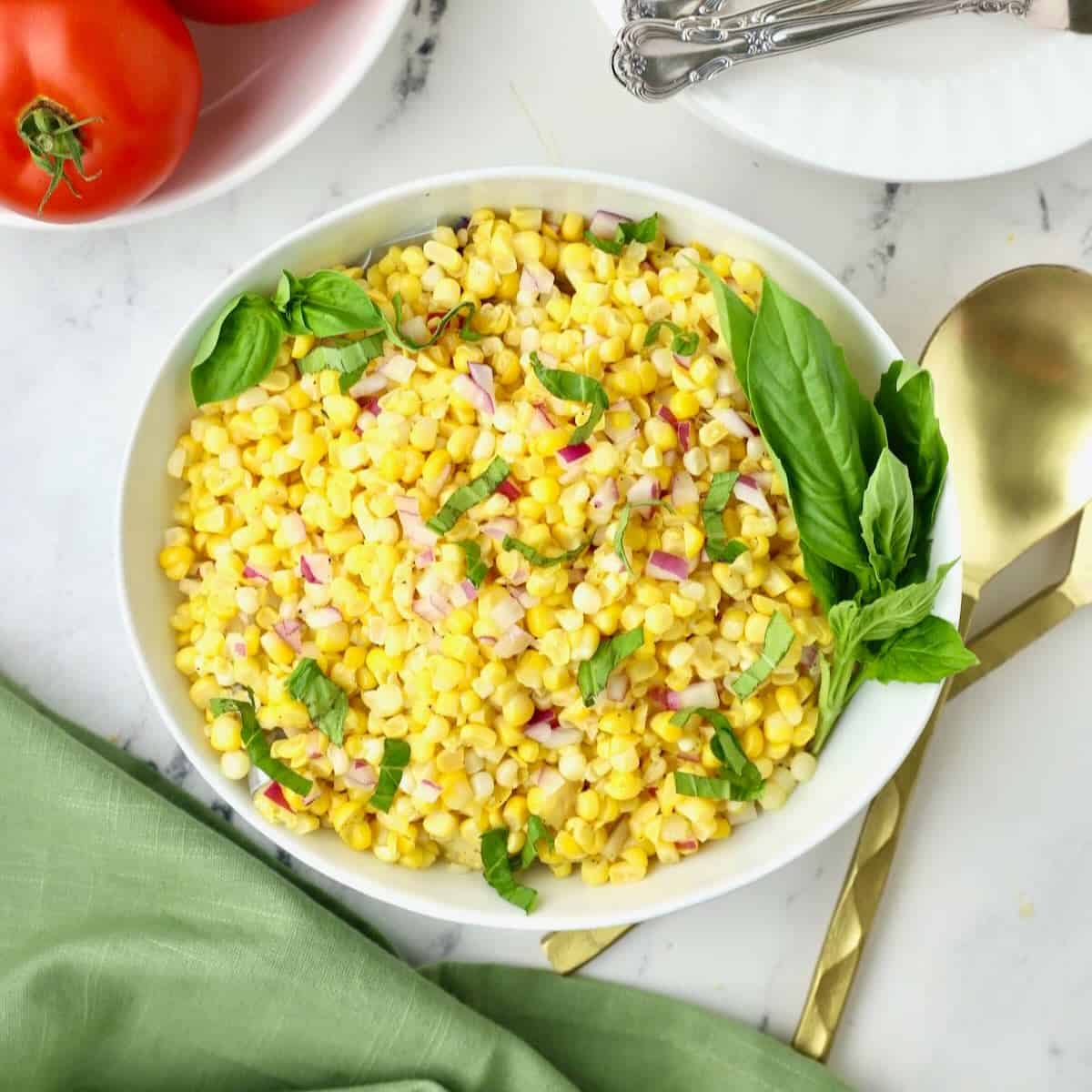 Southern Corn Salad in a white bowl garnished with strips of basil.