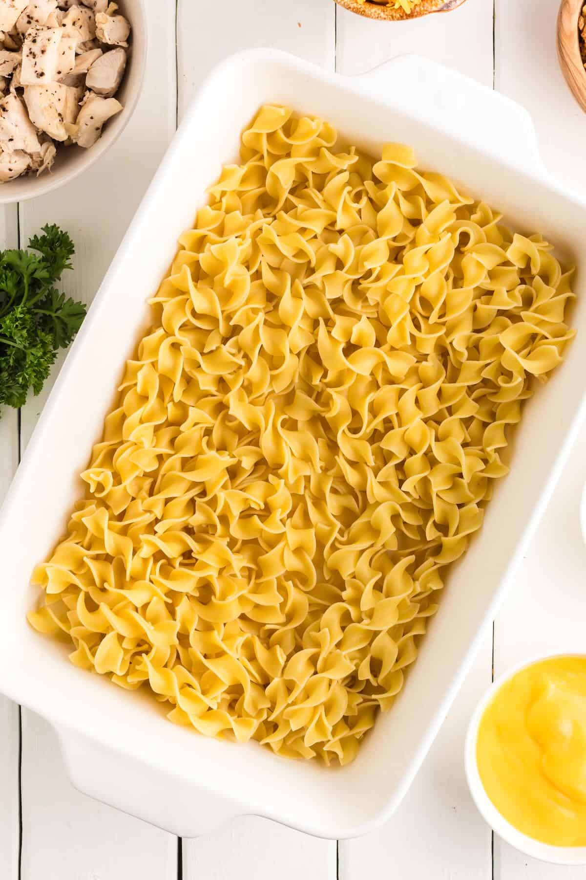A white baking dish full of cooked egg noodles.