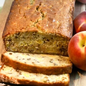 A loaf of peach bread on a cutting board with two slices cut.
