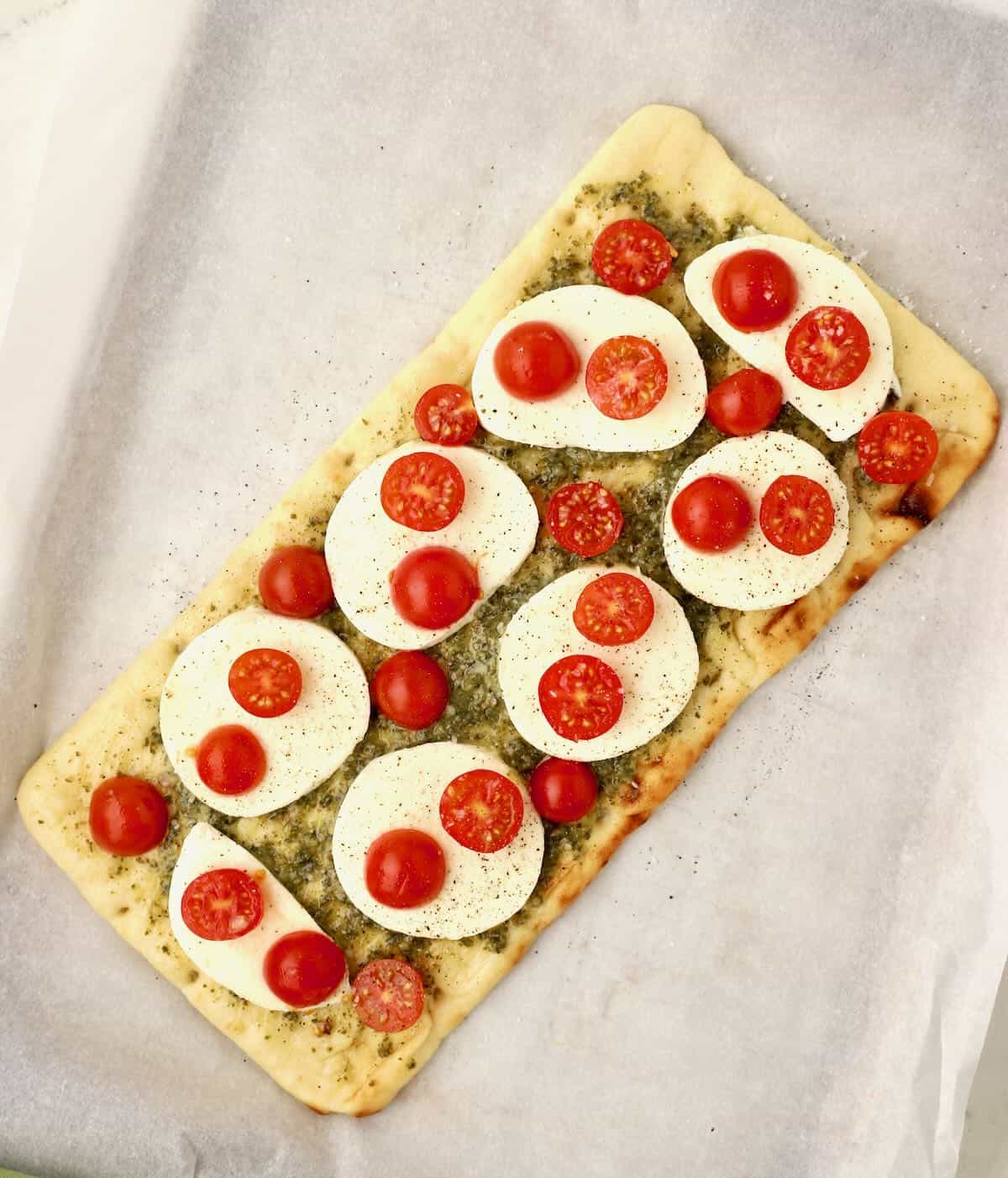 Flatbread topped with fresh mozzarella slices and cherry tomatoes. 