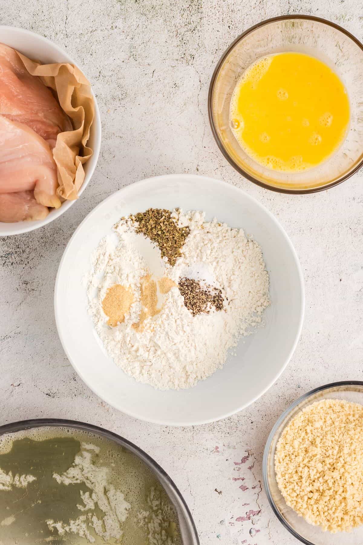 A shallow bowl with flour and various seasonings. 