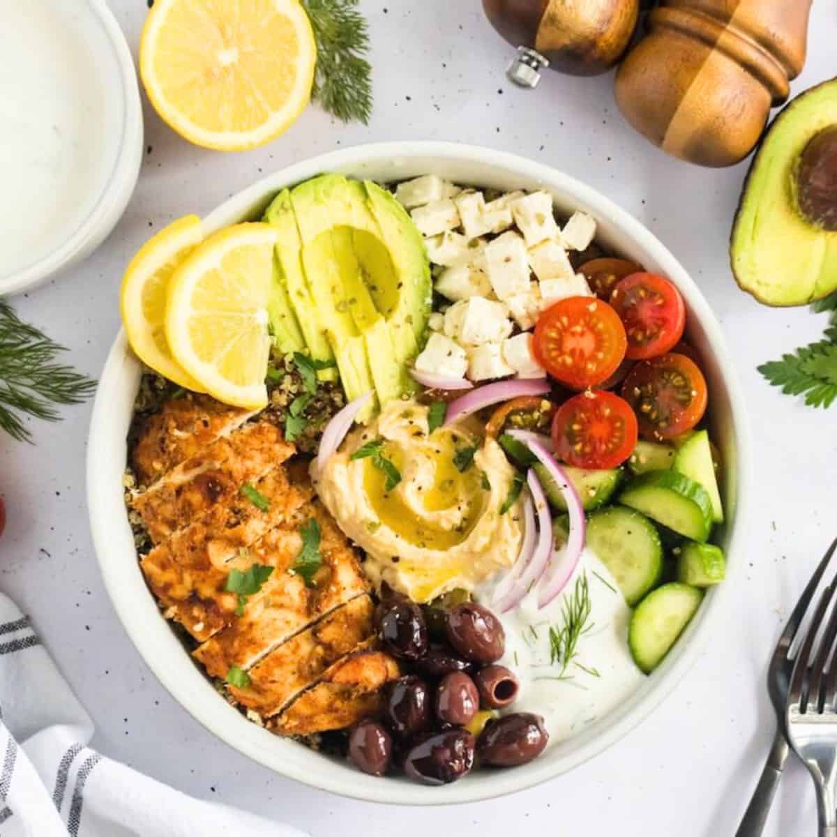 Mediterranean chicken bowl with chicken, avocado, hummus, cucumber, quinoa, tomatoes, and other veggies.