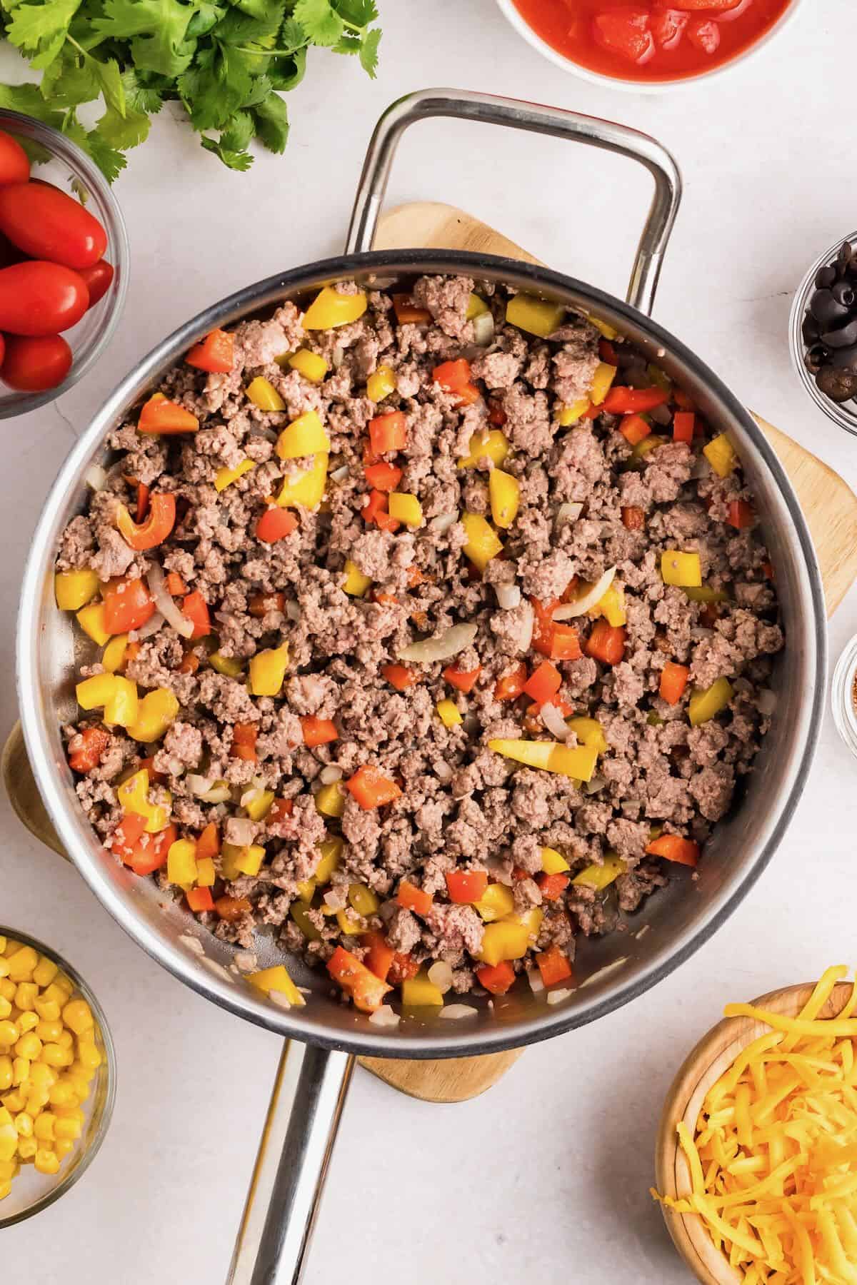 Cooked ground beef, bell peppers and onion in a skillet. 
