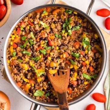 Mexican Beef Rice Skillet in a skillet with a wooden spoon.