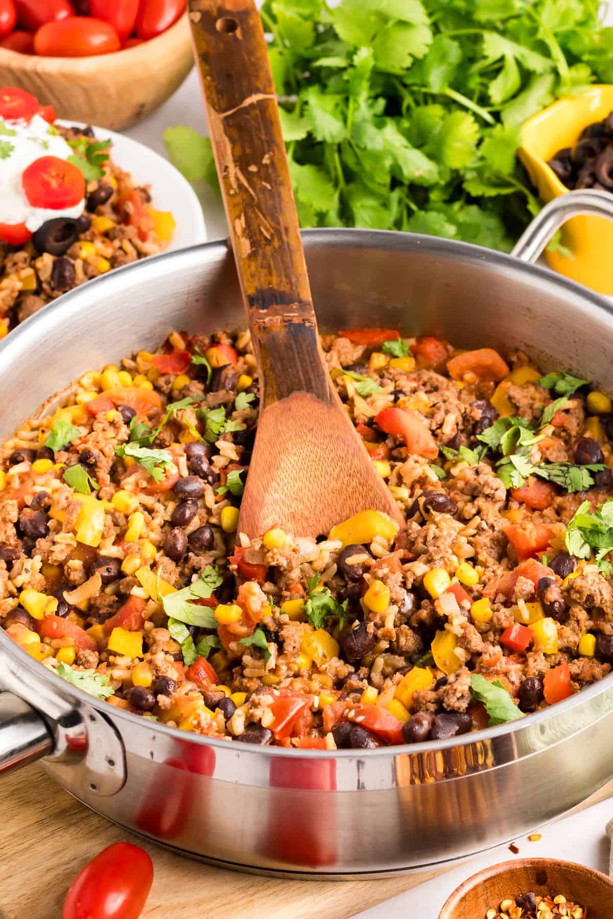 Mexican Beef Rice Skillet in a large skillet with a wooden spoon. 