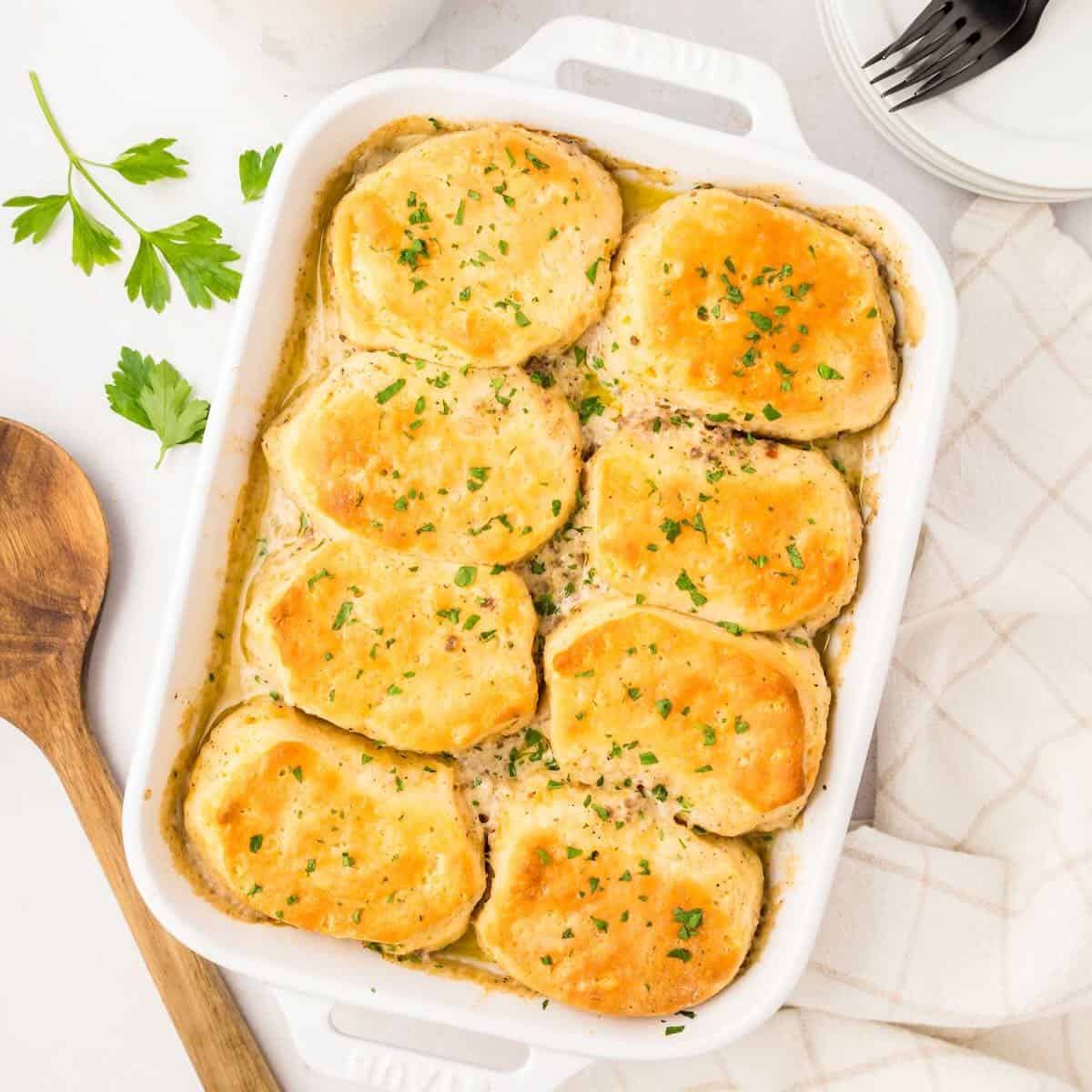 Sausage Gravy Breakfast Casserole topped with biscuits in a white casserole dish.