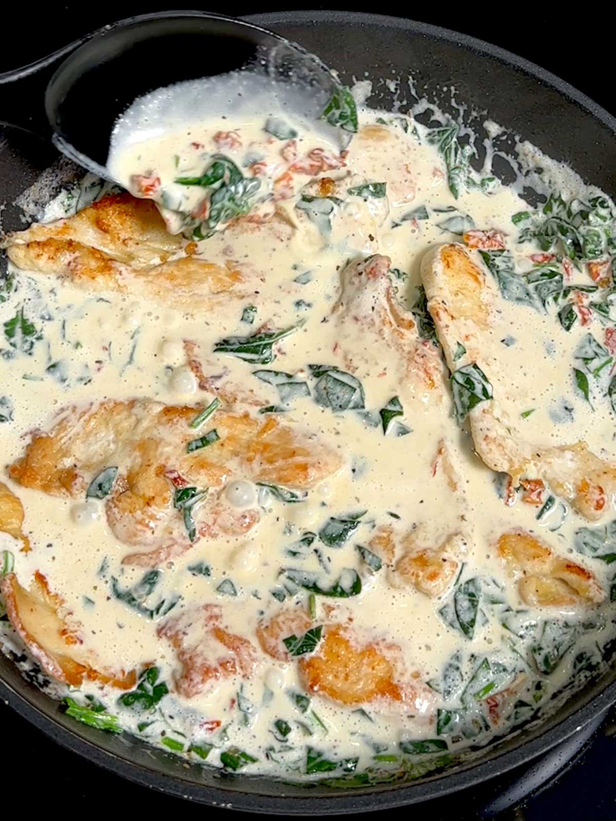A skillet full of creamy Tuscan chicken with spinach. 