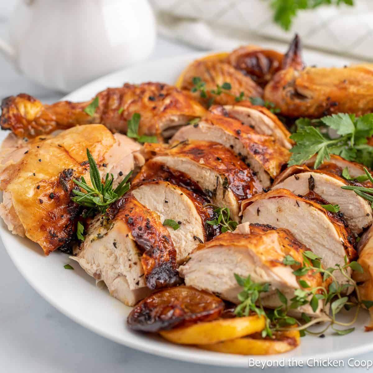 A cut up roasted chicken displayed on a white serving platter. 