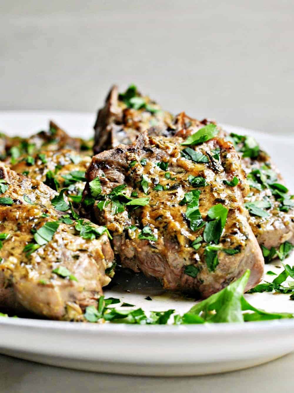 Baked lamb chops on a serving platter garnished with parsley.
