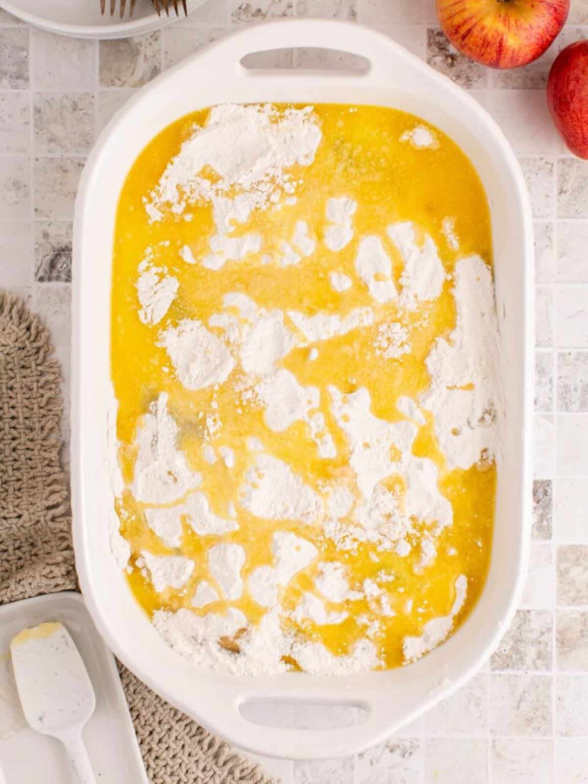 Melted butter covering dry cake mix in a baking dish.