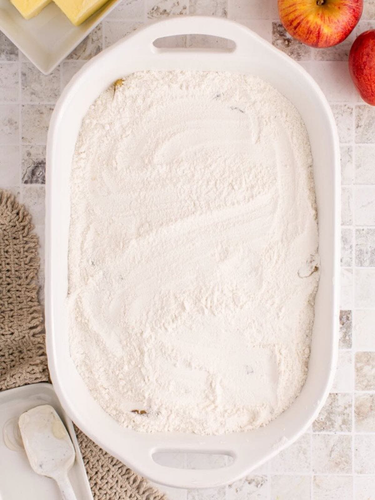 Dry yellow cake mix spread over pie filling in a white baking dish. 