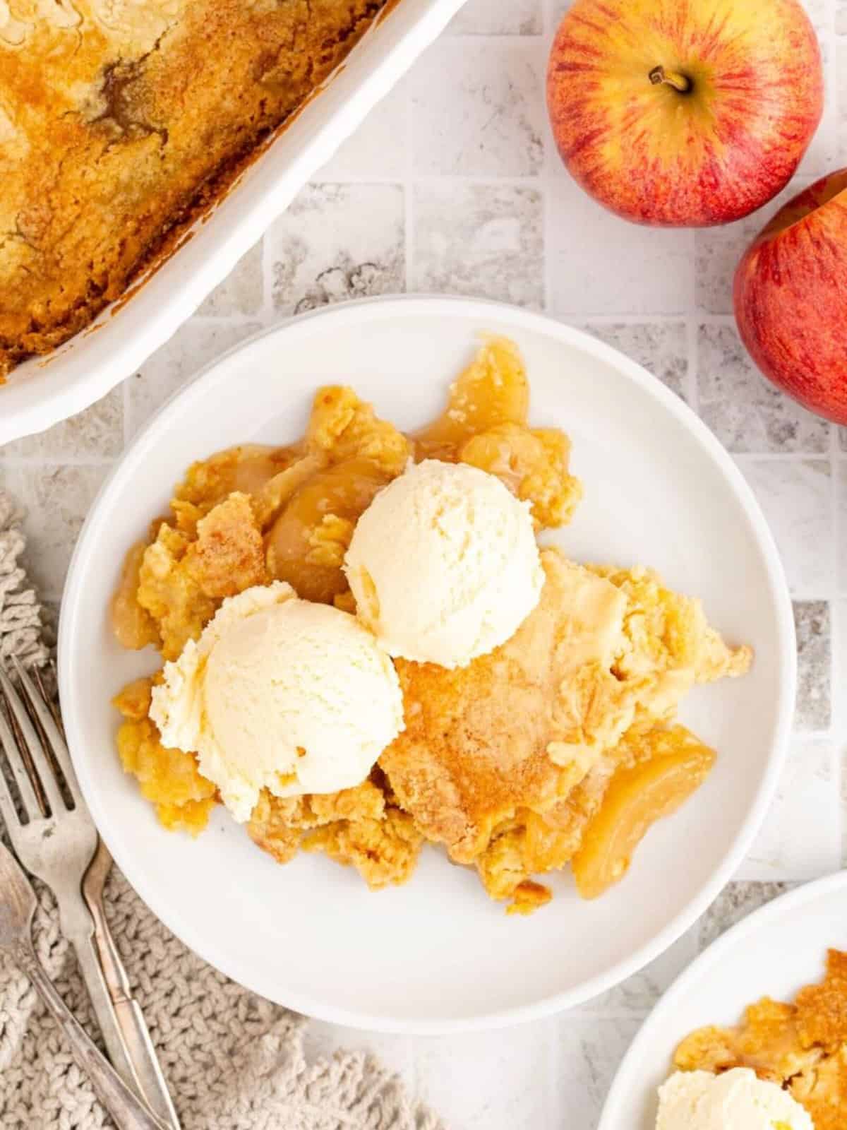 A serving of apple cobbler with two scoops of vanilla ice cream on top. 