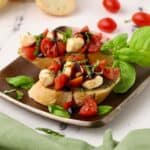 Caprese Bruschetta is a Caprese salad on toast with pesto topped with basil.