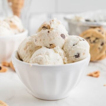 Scoops of cookie dough ice cream with chocolate chips in a white bowl.