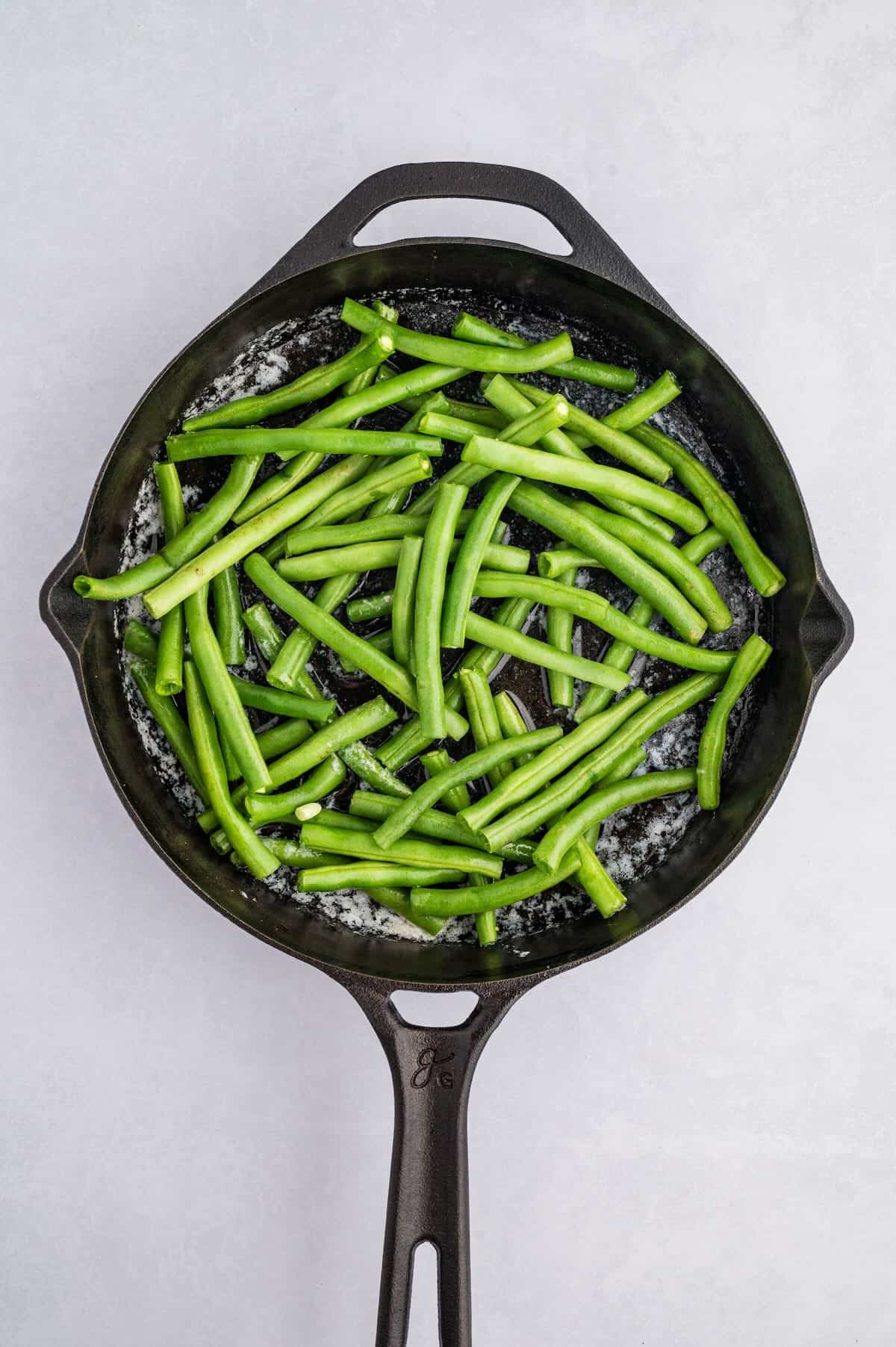 Fresh green beans in a cast iron skillet with melted butter. 