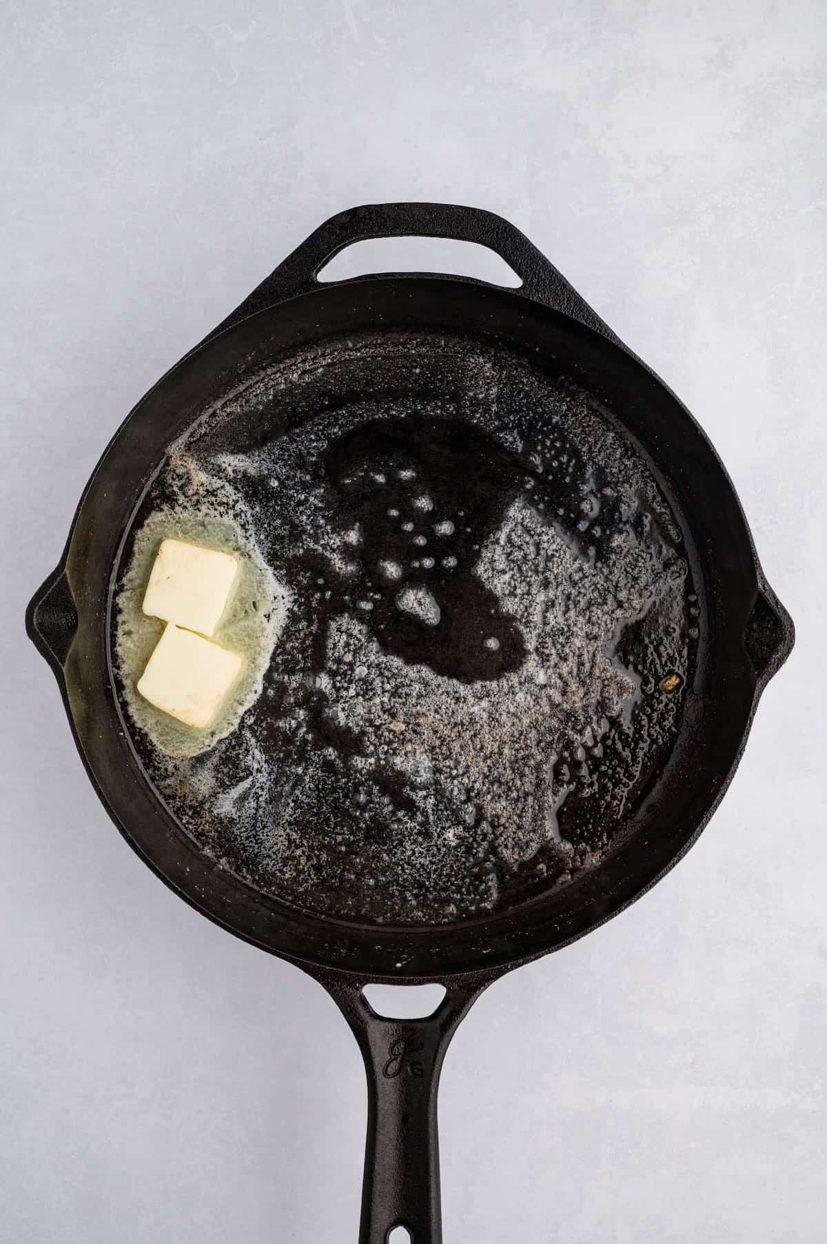 A cast iron skillet with melted butter. 