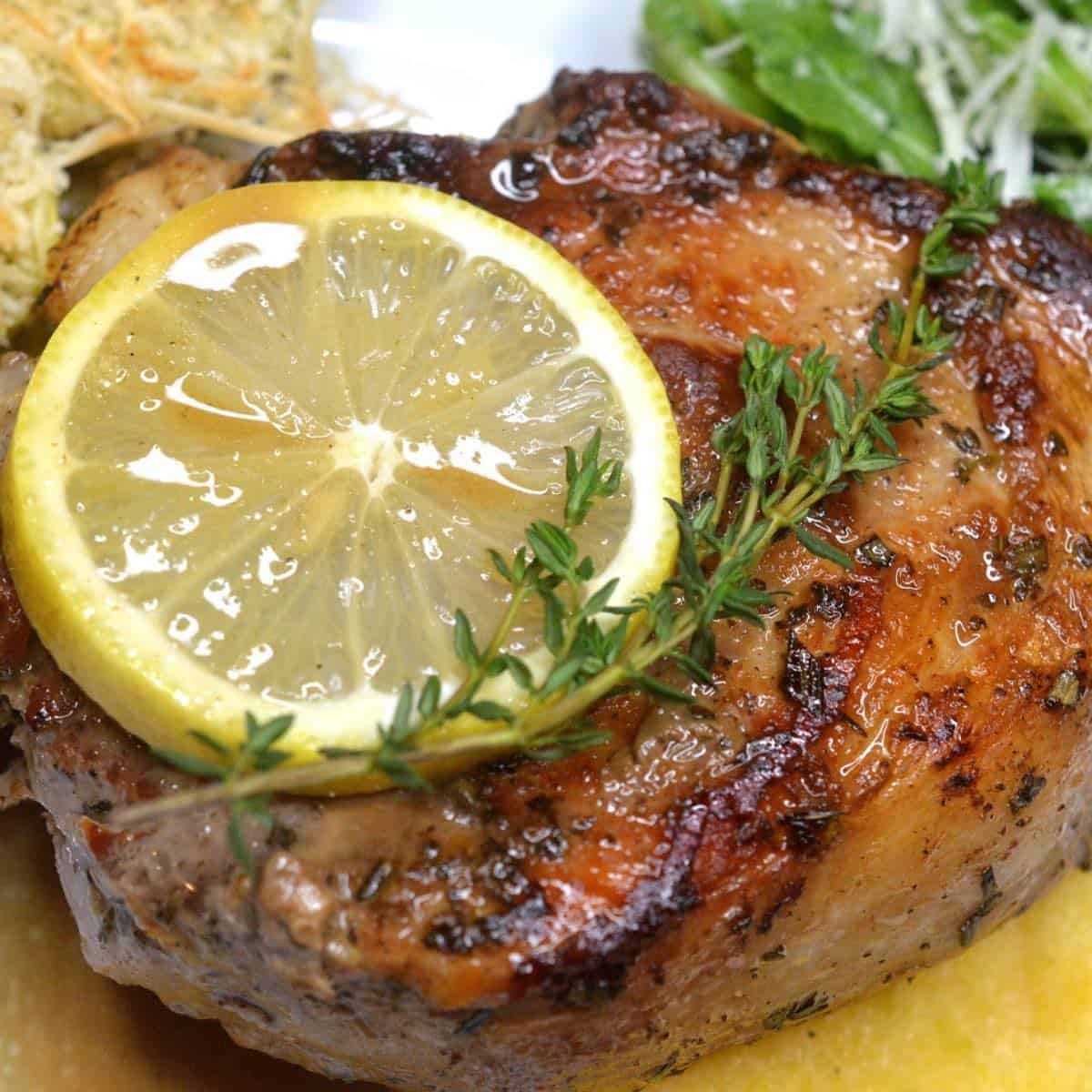 A pan-seared veal chop on a plate topped with a wine sauce. 
