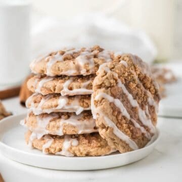 A stack of coffee cake cookies with vanilla glaze on a white plate.