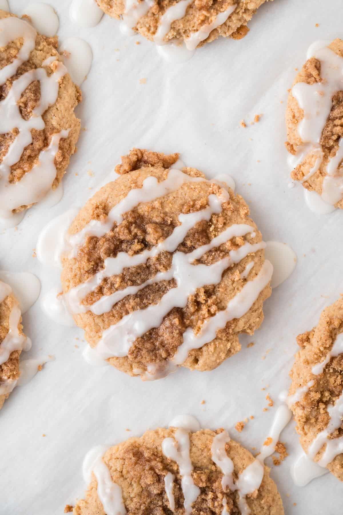 Coffee cake cookies on a cookie sheet topped with streusel and icing. 