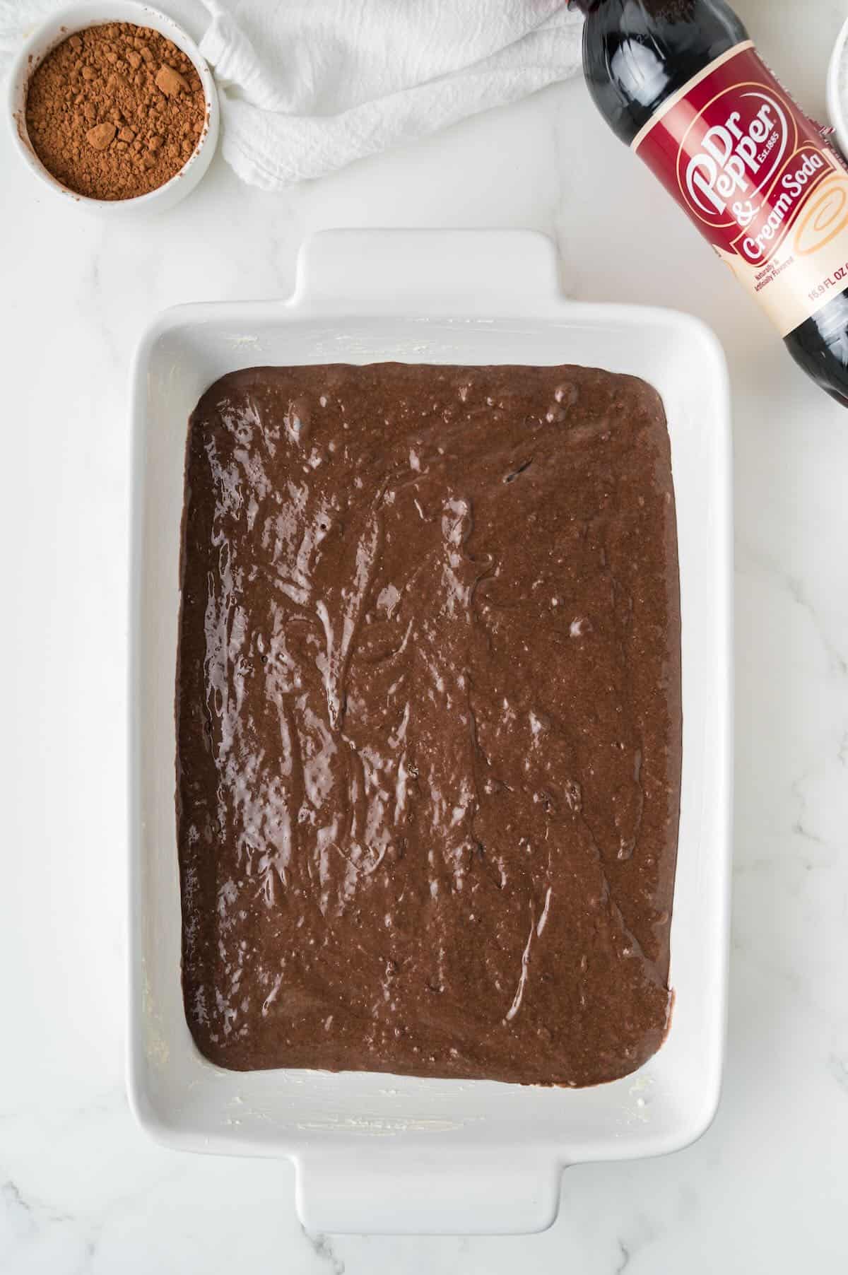 Chocolate cake batter in a white rectangle baking dish. 