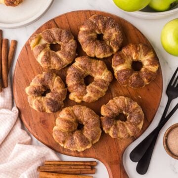 Apple pastries on a wooden cutting board.