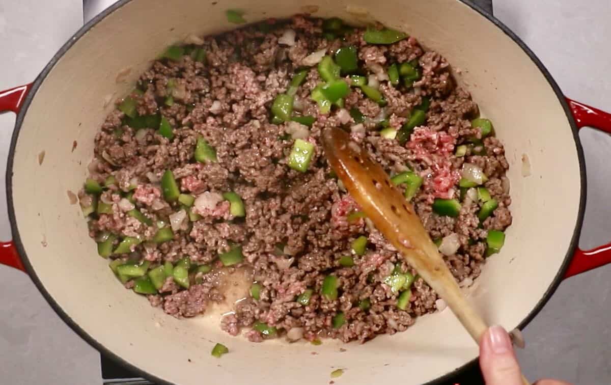 A Dutch oven with browned ground beef, bell pepper and onion. 