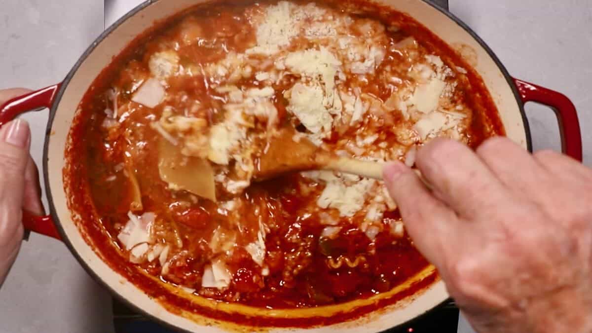 Lasagna soup in a Dutch oven with parmesan cheese added and mixed in.