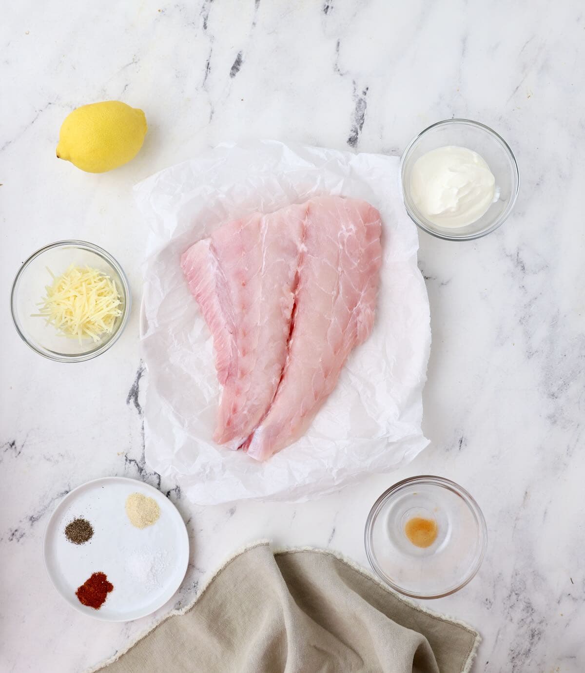 Ingredients for baked grouper include a large grouper fillet, sour cream and parmesan cheese. 
