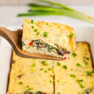 A slice of cottage cheese egg bake on a serving spatula over the baked casserole.