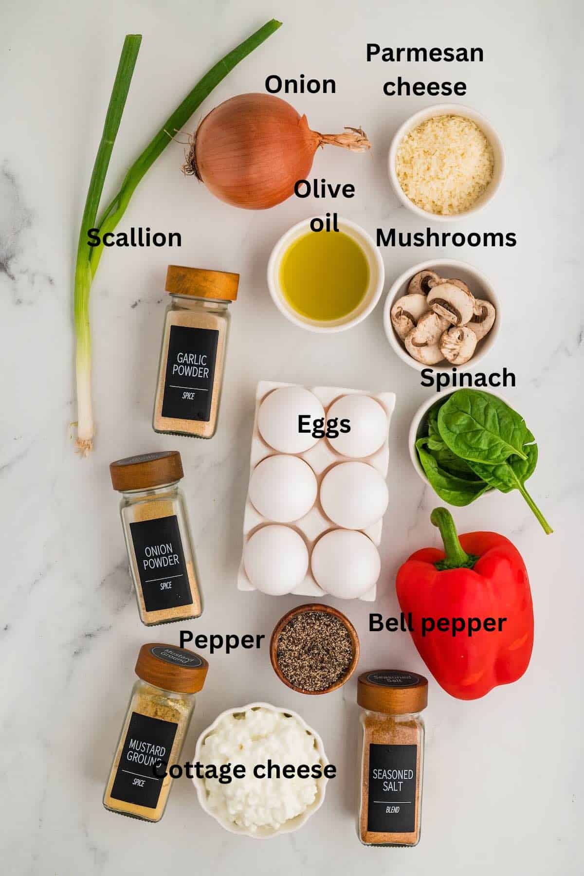 Ingredients on a counter including spinach, mushrooms, eggs, cottage cheese and seasonings. 