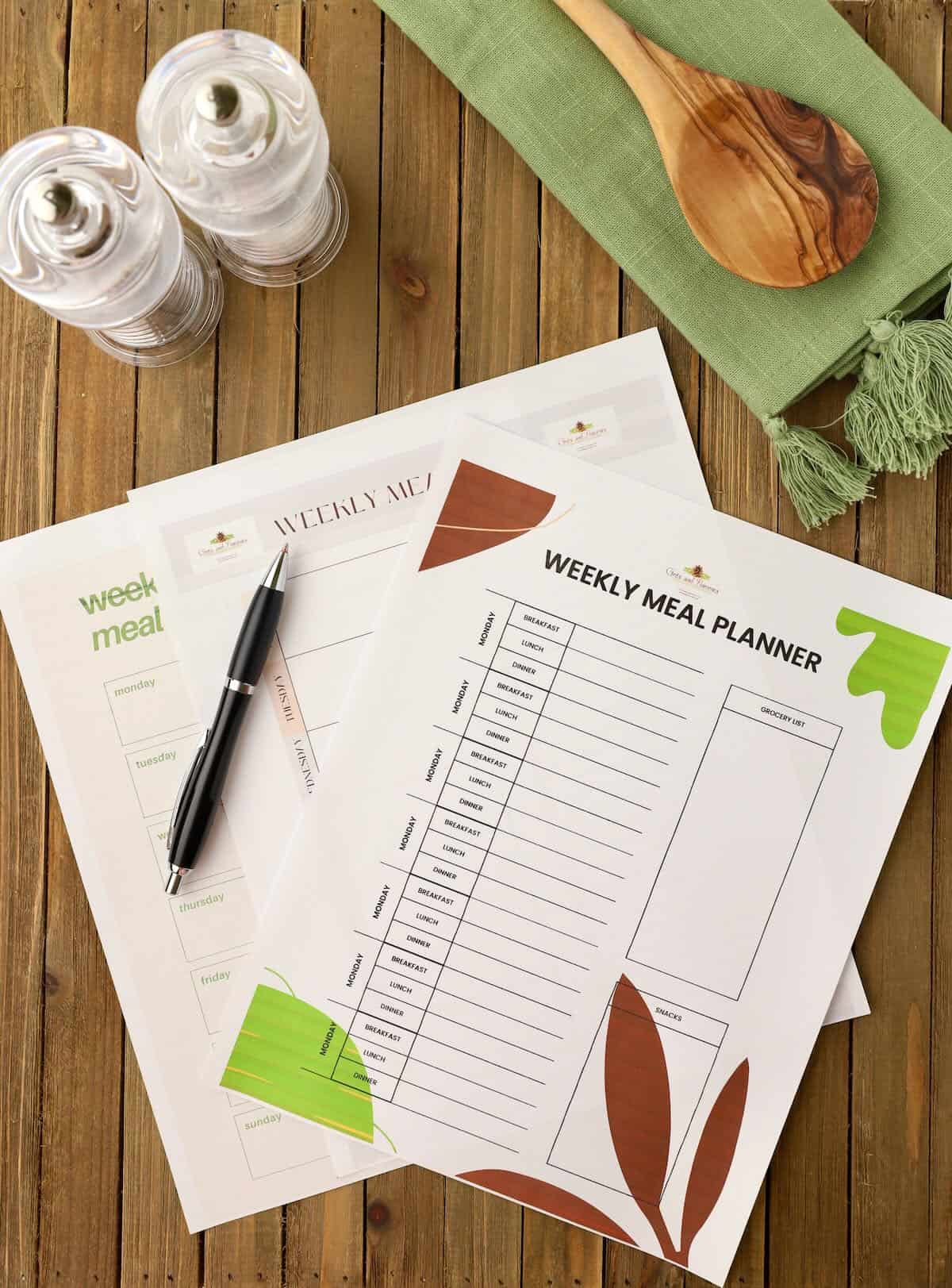 Three blank Meal Planning Templates on a wooden cutting board with a pen.