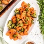 A white oval dish full of roasted broccoli and carrots.