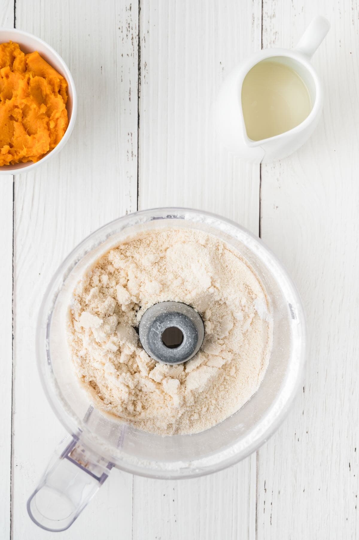 Flour and other dry ingredients mixed with butter in a food processor.
