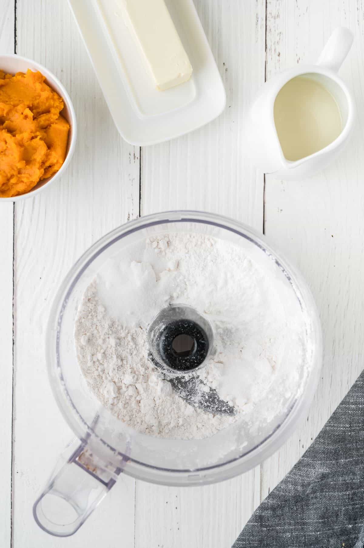 Flour and other dry ingredients in the bowl of a food processor. 