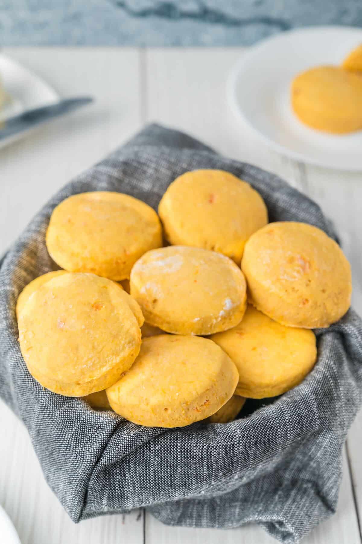 A basket with a blue napkin full of sweet potato biscuits.