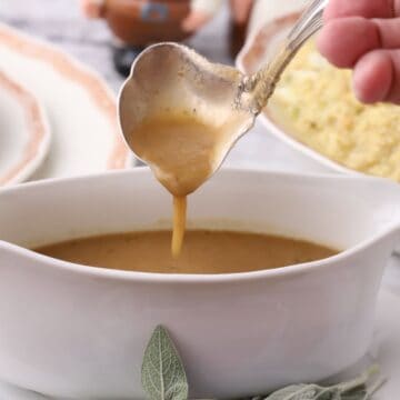A gravy boat full of Turkey Neck Gravy with a gravy ladle.