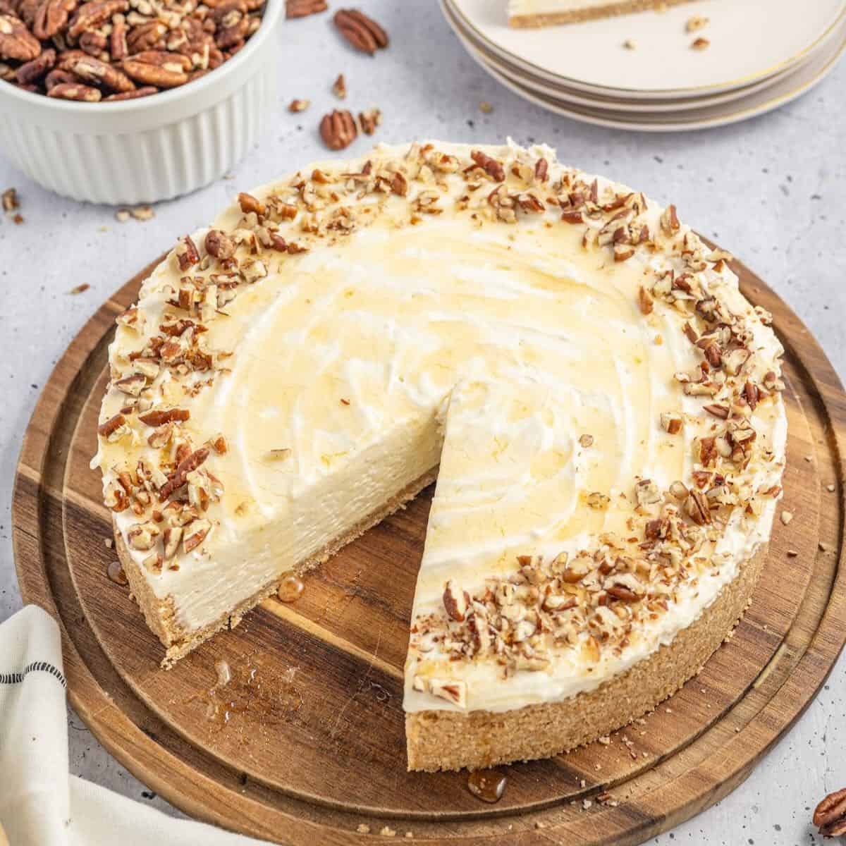 A No-Bake Honey Cheesecake on a wooden cutting board with a slice cut out.