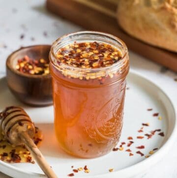 A small jar full of hot honey with crushed red pepper flakes.