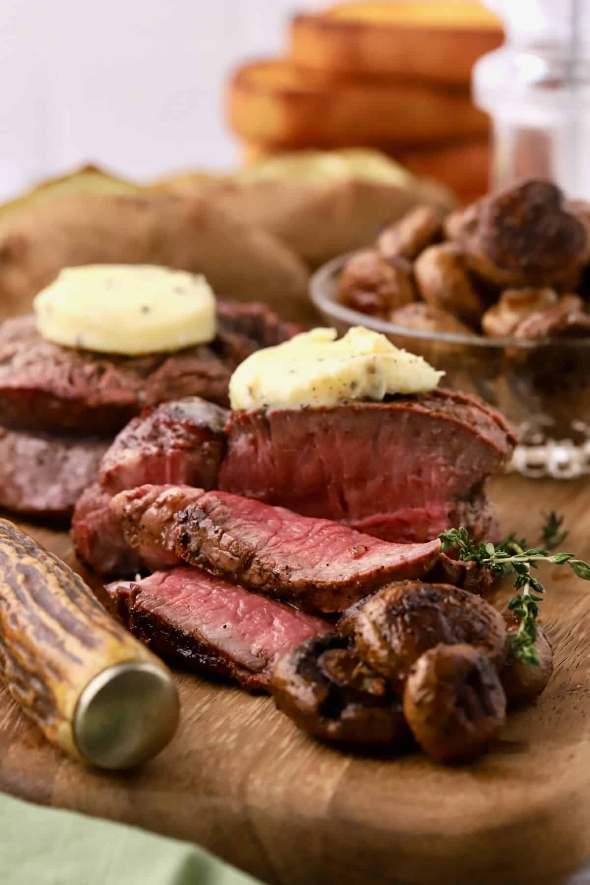 A grilled filet mignon steak sliced on a cutting board.