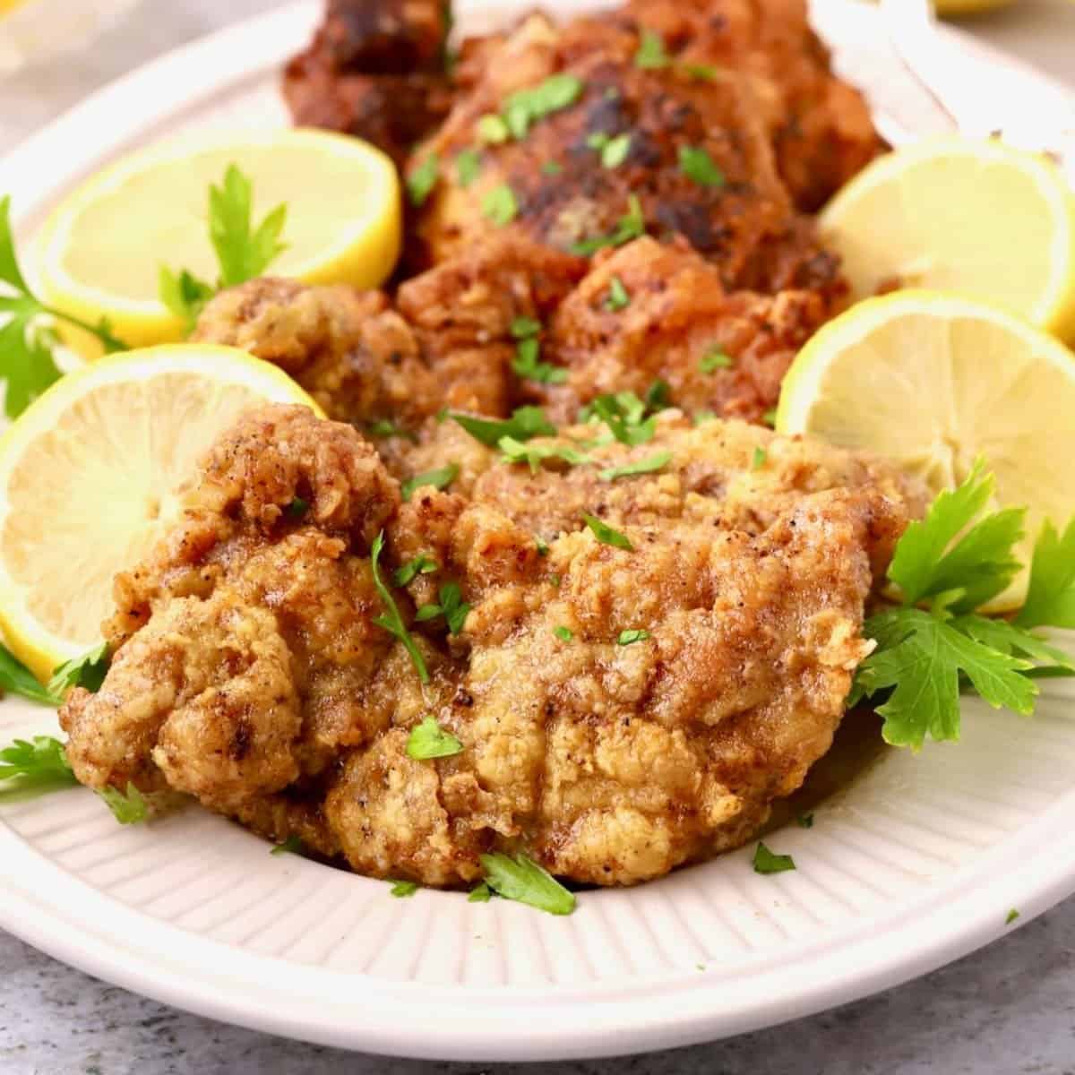 Lemon pepper chicken thighs garnished with lemon slices and parsley.