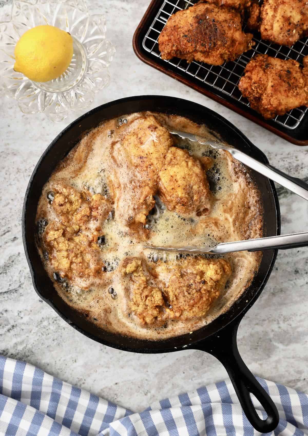 Floured chicken thighs frying in a cast iron skillet. 