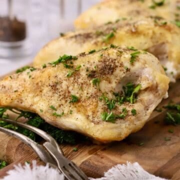 Oven baked bone-in chicken breasts on a cutting board garnished with parsley.