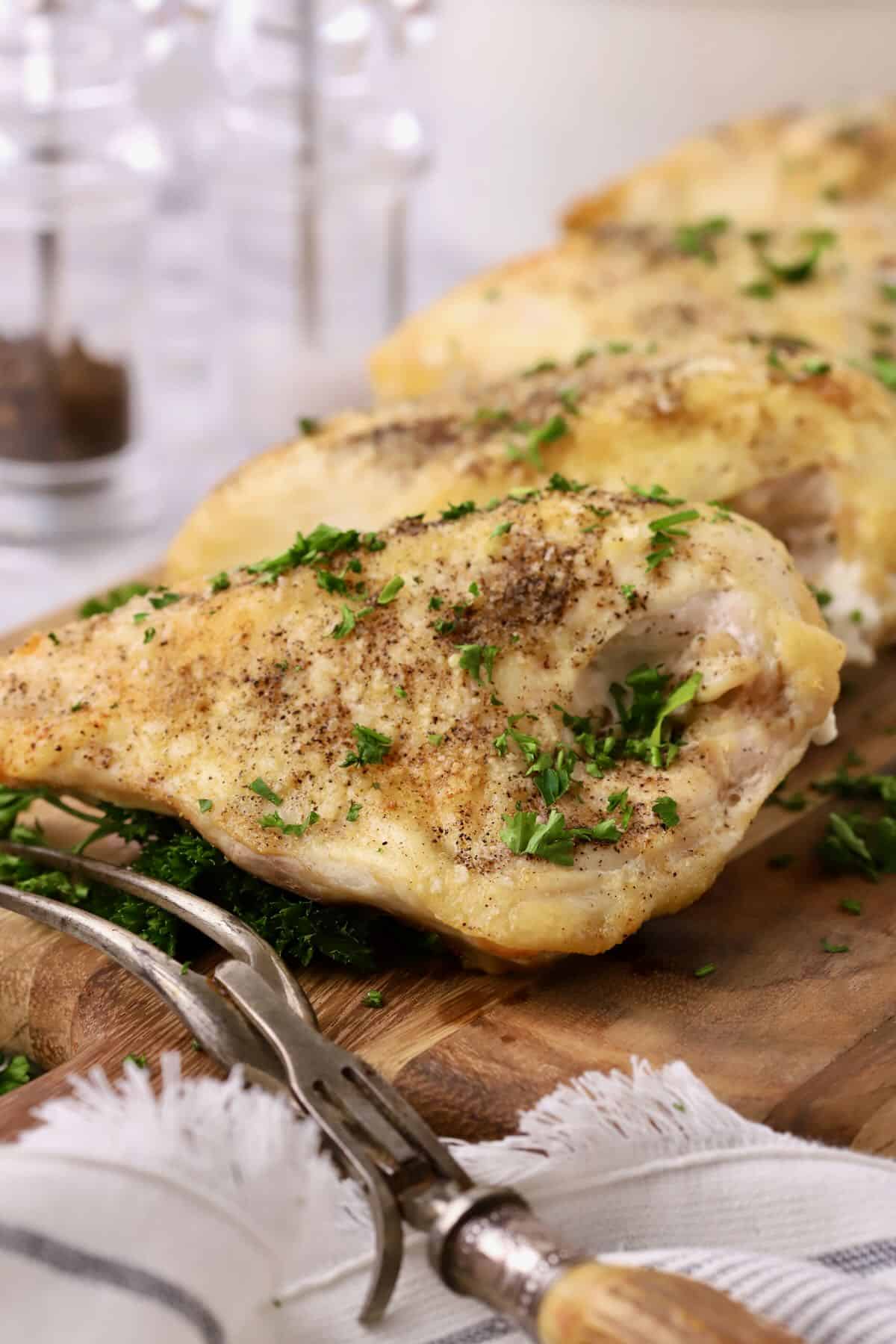 Baked bone-in chicken breasts on a cutting board.