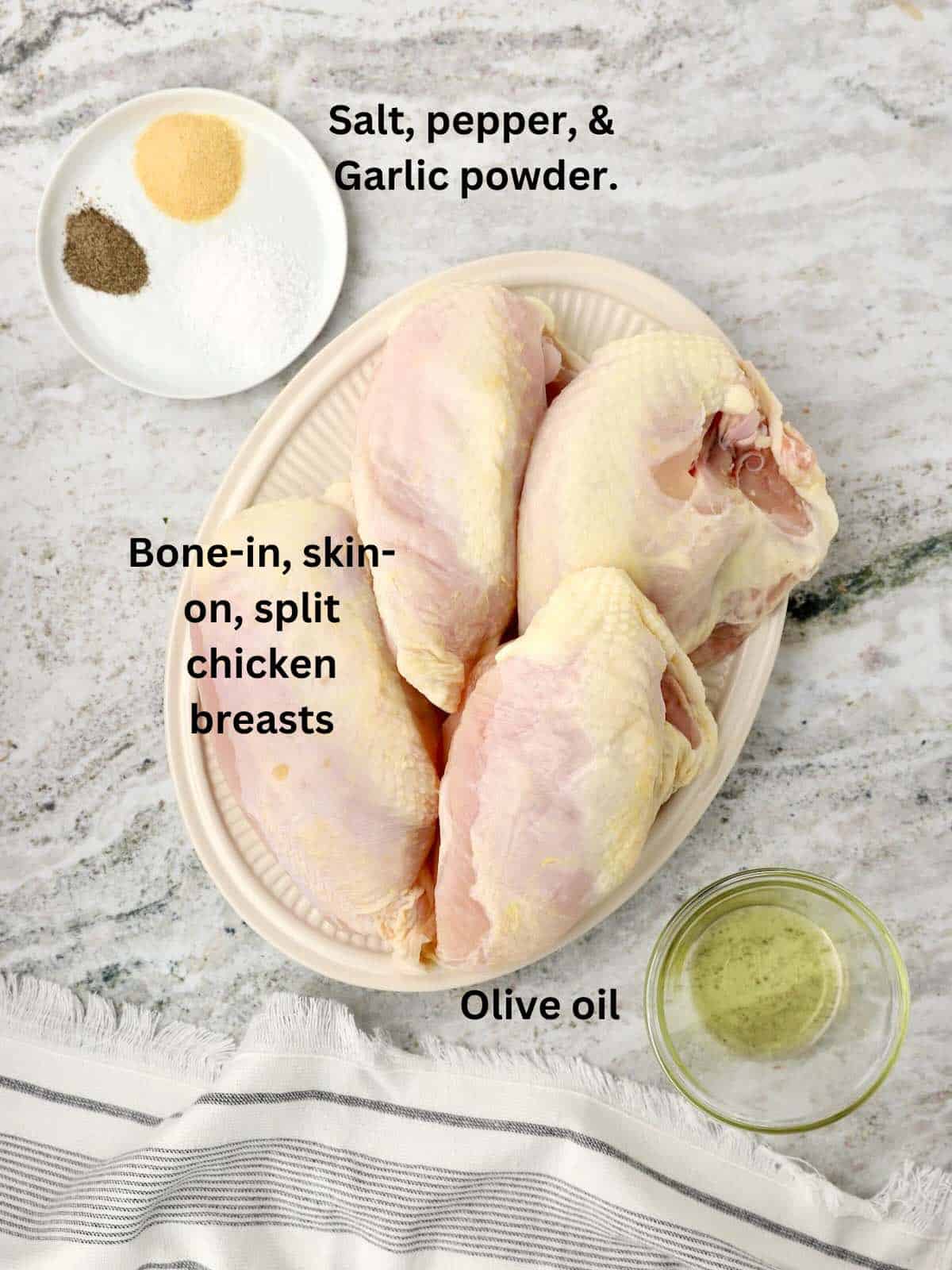 Raw chicken breasts on a plate along with seasonings and olive oil.