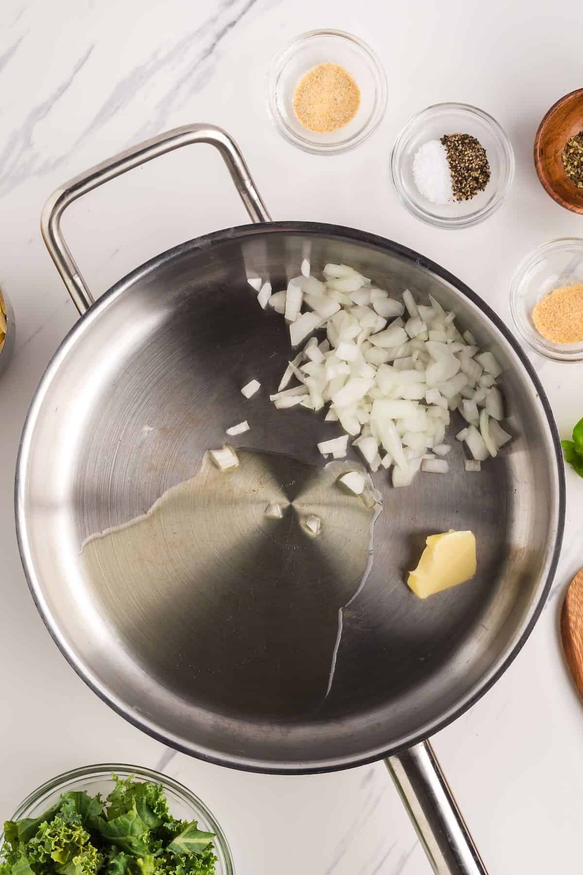 Chopped onions and garlic are sauteing in a skillet.
