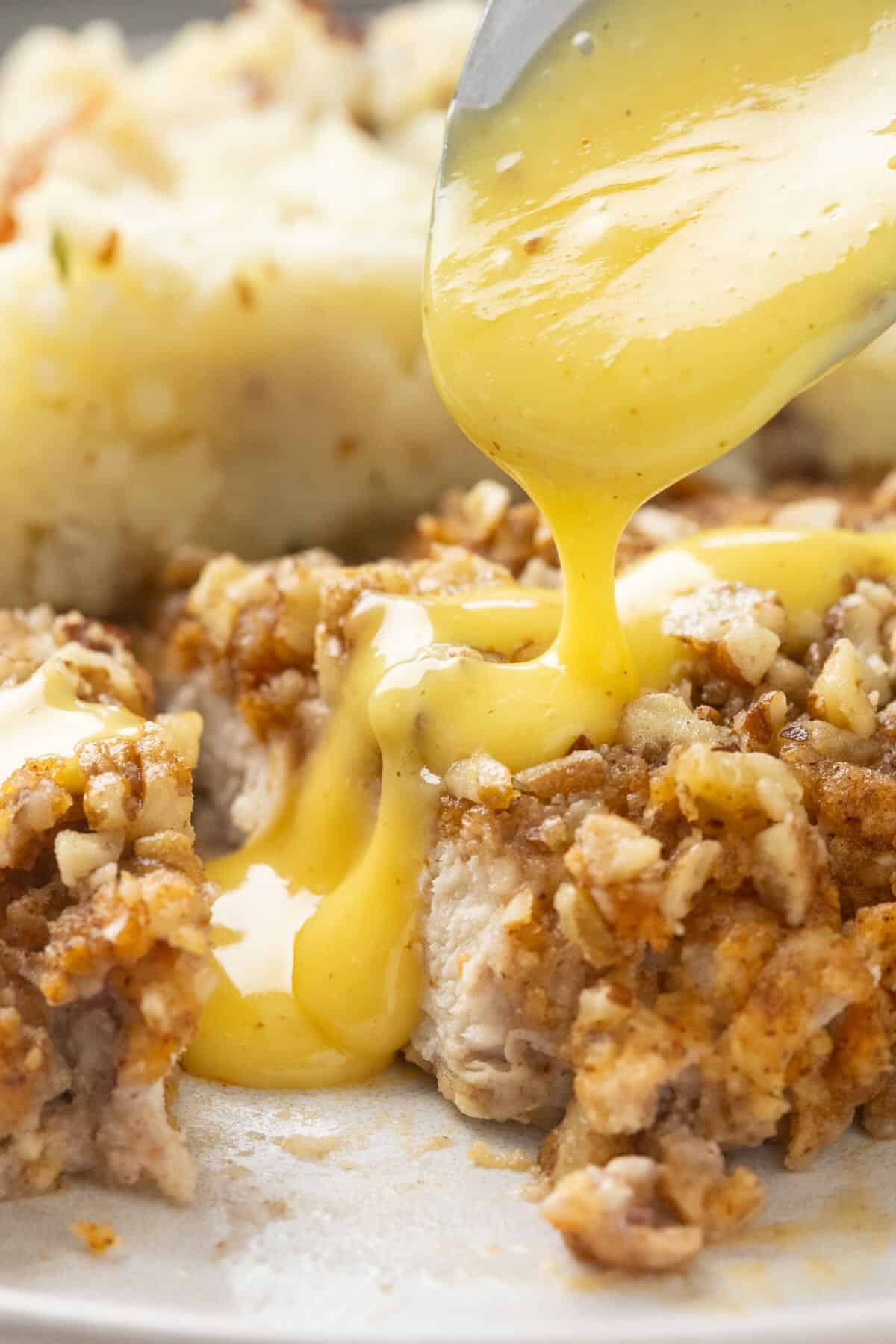 Honey mustard sauce is drizzled on slices of pecan-crusted chicken.