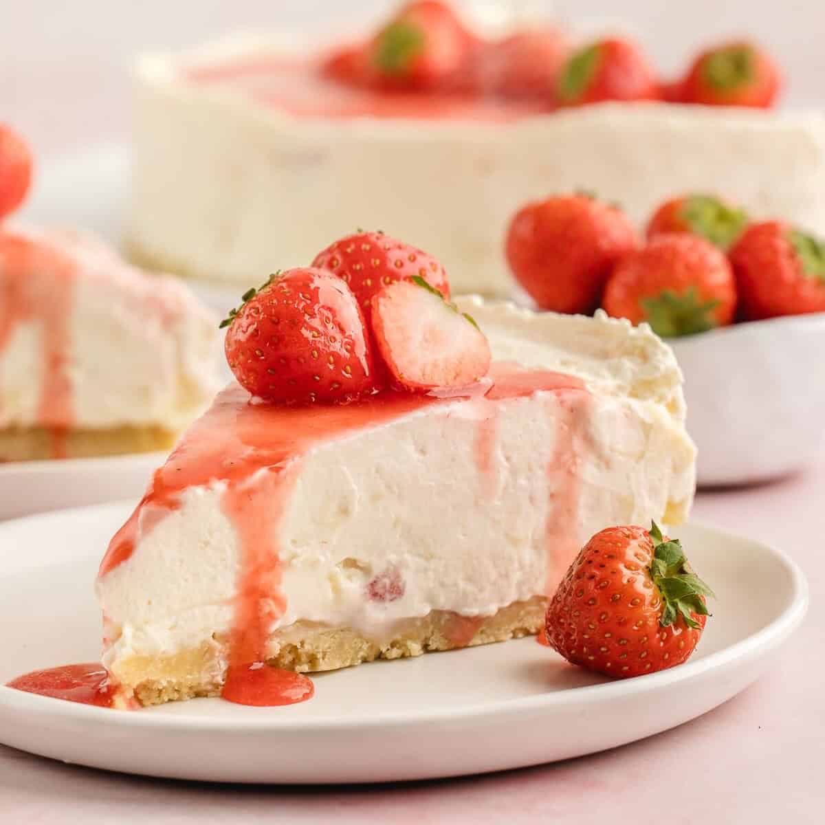 A slice of White Chocolate and Strawberry Cheesecake topped with strawberry sauce on a white plate.