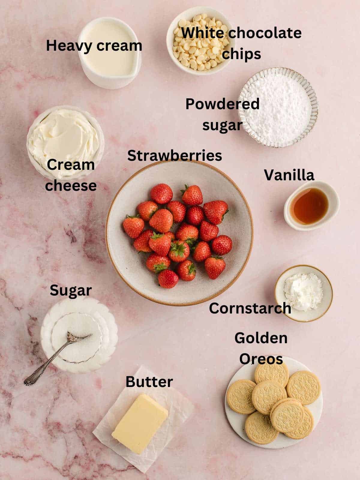 Bowls of strawberries, cream cheese, sugar, vanilla extract, and heavy cream along with Oreo cookies and butter. 